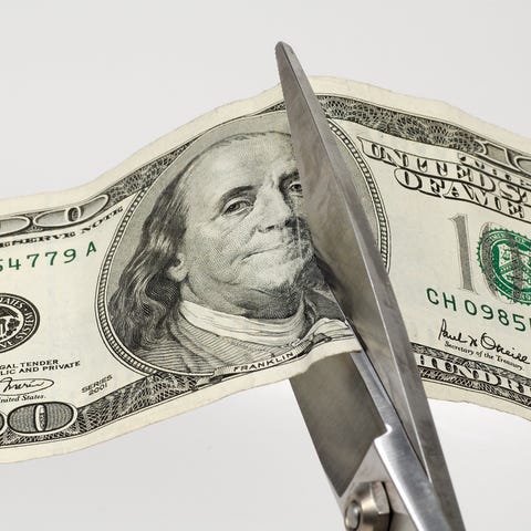 Scissors cutting a one hundred dollar bill in half