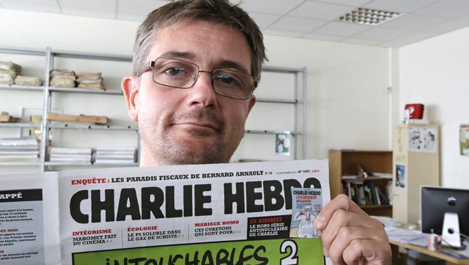 FILE - In this Sept.19, 2012 file photo, Charb , Stephane Charbonnier, the publishing director of the satyric weekly Charlie Hebdo, displays the front page of the newspaper as he poses for photographers in Paris. Masked gunmen shouting ìAllahu akbar!î stormed the Paris offices of a satirical newspaper Wednesday Jan.7, 2015, killing 12 people including Charb, before escaping. It was France's deadliest terror attack in at least two decades. (AP Photo/Michel Euler, File) ORG XMIT: XPAR102
