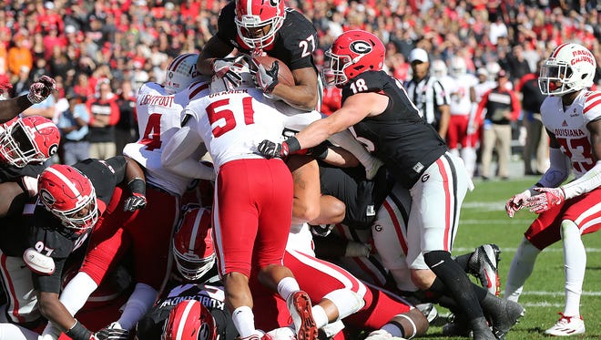 Georgia tailback Nick Chubb goes over the top of the pile and Louisiana-Lafayette defender Trey Granier for a touchdown during the fourth quarter in an NCAA college football game on Saturday, Nov. 19, 2016, in Athens, Ga.