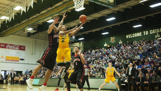 Vermont's Trae Bell-Haynes (2) leaps past Northeastern's T.J. Williams (10) for a layup during the men's basketball game between the Northeastern Huskies and the Vermont Catamounts at Patrick Gym on Saturday afternoon.
