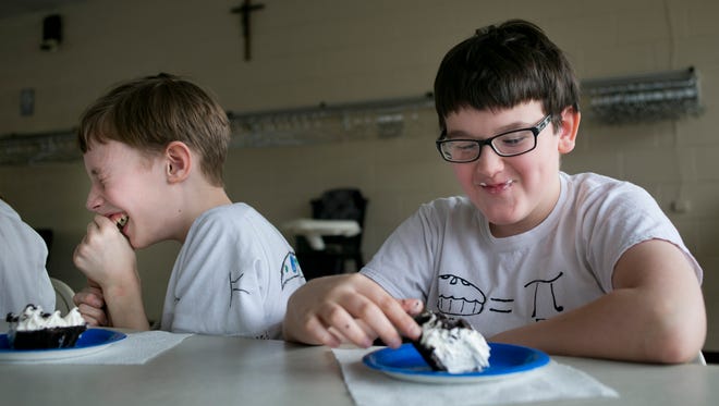 Sixth-grade student Eric Bostick, 12, left, laughs after Jeremy Ranshaw, 11, ate a piece of pie with his hands during Pi Day at St. Mary’s Catholic School in St. Clair.
