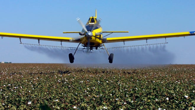 FILE - In this Sept. 25, 2001 file photo, a crop dusting plane from Blair Air Service dusts cotton crops in Lemoore, Calif. California regulators have announced a new rule that bans farmers from using certain pesticides near schools and day care centers. The state's Department of Pesticide Regulation announced the new rule Tuesday, Nov. 7, 2017. The department says the new regulation is among the strictest pesticide in the U.S.