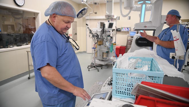 Scott Pinion, left, a radiologic technologist, and registered nurse Marty Heason, right, prepare the hybrid operating room for a surgery at Bon Secours St. Francis hospital on Monday.
