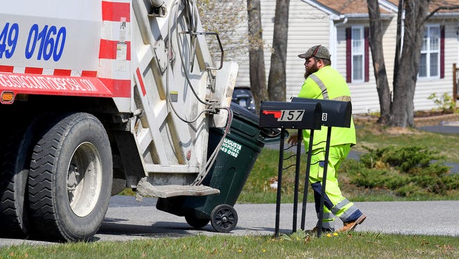A sanitation crew makes the rounds and retrieves the trash from trashcans placed in front of the various homes in the neighborhood along China Clay Road, not far from Brookmill Road, in Augusta County.
