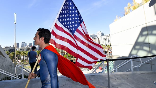 Bersain Gutierrez, dressed as Superman, carries an American flag during preview night at the 2014 Comic-Con International Convention held Wednesday, July 23, 2014 in San Diego.