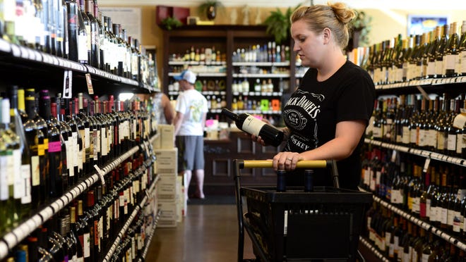 Tiffany Farmer restocks the shelves at Fusion Wine and Spirits in Milton.