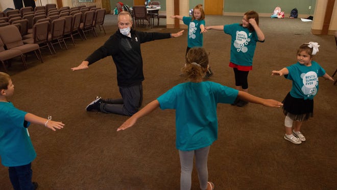 John Mugler, CEO of YMCA Topeka, leads kids in what he called "The Helicopter Game" on Thursday as a means to illustrate keeping social distance at Covanent Baptist Church during a YMCA extended summer camp.