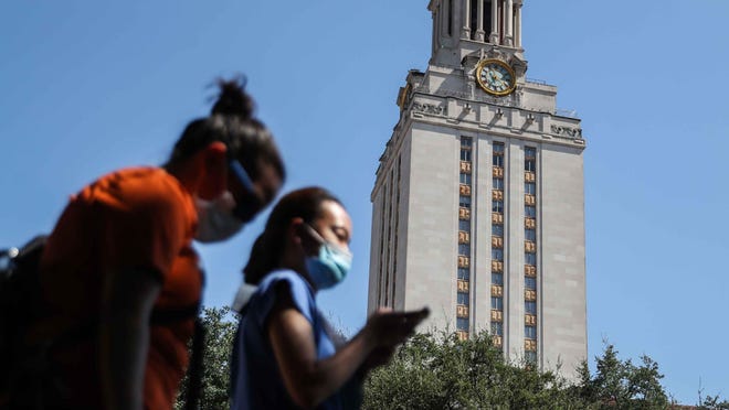 People wear masks as they pass in front of the UT Tower in Austin on Friday, August 21, 2020.