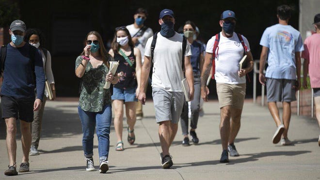 North Carolina State University students wearing face coverings walk behind Dabney Hall to the Free Expression Tunnel on Tuesday, Aug. 18, 2020 in Raleigh, N.C. The university announced Thursday, Aug. 20, 2020, it will move all undergraduate classes online starting on Monday due to COVID-19 clusters.
