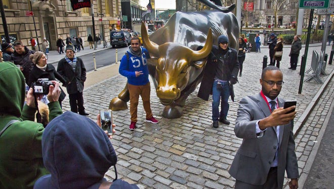 Visitors take photos of themselves with the "Charging Bull" sculpture in Wall Street's financial district, Wednesday, Dec. 17, 2014, in New York.