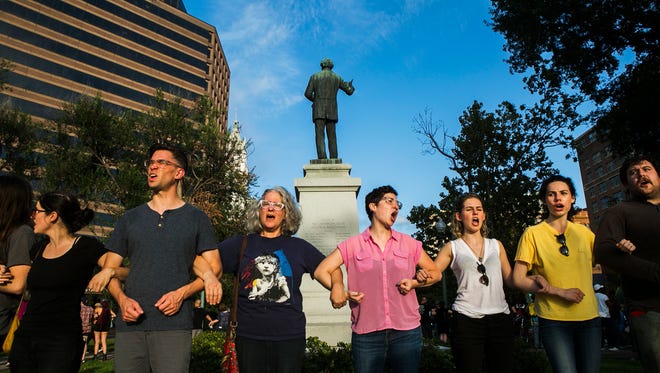 Protesters link arms as they surround the Jefferson Davis Confederate statue at Memphis Park on Tuesday. The action comes days following the death of Heather Heyer following the "Unite the Right" rally in Charlottesville, Virginia.