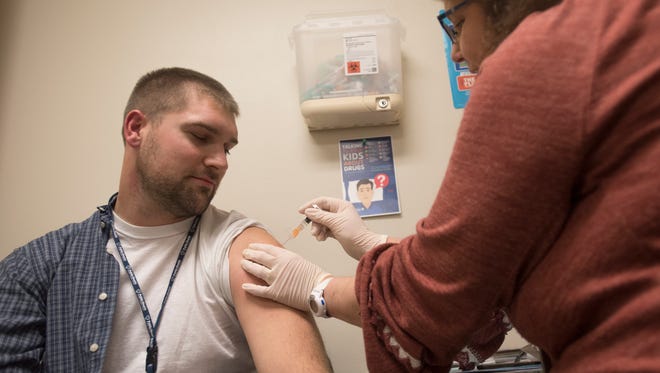 Chris Carver, left, receives his first flu shot ever at the Ross County Health District walk-in clinic. “My wife is having a baby and is a nurse so she is making sure we all stay healthy,” said Carver.