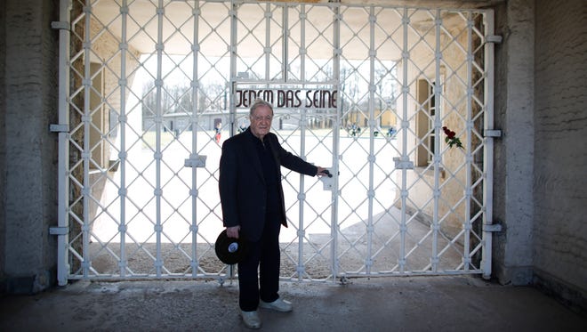 In this Friday, April 10, 2015, photo Henry Oster poses at the gate of the former Nazi concentration camp Buchenwald with the inscription “Jedem das Seine” (“To each his own”) on the eve of the 70th anniversary of the liberation of the camp in Weimar, eastern Germany.