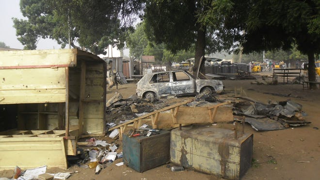 A child, at rear, walks through the scene of an explosion in a mobile phone market in Potiskum, Nigeria, Monday Jan. 12, 2015. Two female suicide bombers targeted the busy marketplace on Sunday. (AP Photo/Adamu Adamu)
