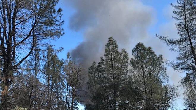 A plume of smoke rises into the air Monday from a fire to destroy a Happy Valley barn where authorities found a stockpile of explosives.