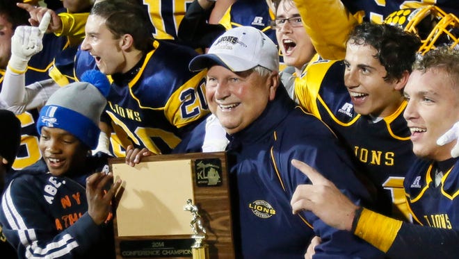 South Lyon football coach Mark Thomas holds the district championship trophy after a 17-7 win over Plymouth Canton on Oct. 17, 2014.