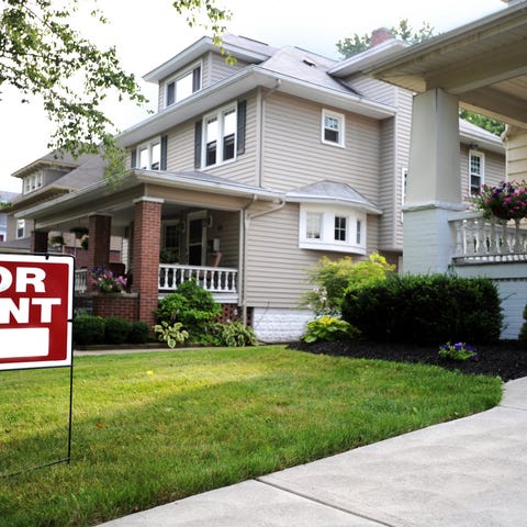 A row of homes shown with a For Rent sign in one f