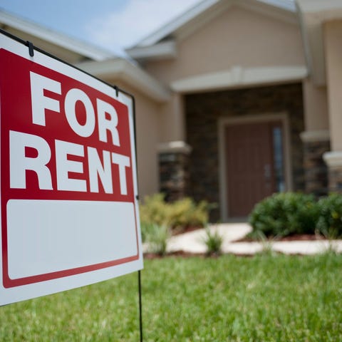 A "for rent" sign in the front lawn of a house.