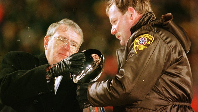 General manager Ron Wolf and coach Mike Holmgren celebrate the Super Bowl XXXI win at Lambeau Field.  Holmgren was loaned a sheriff deputy's jacket because he had no heavy coat for the chilly parade through Green Bay.