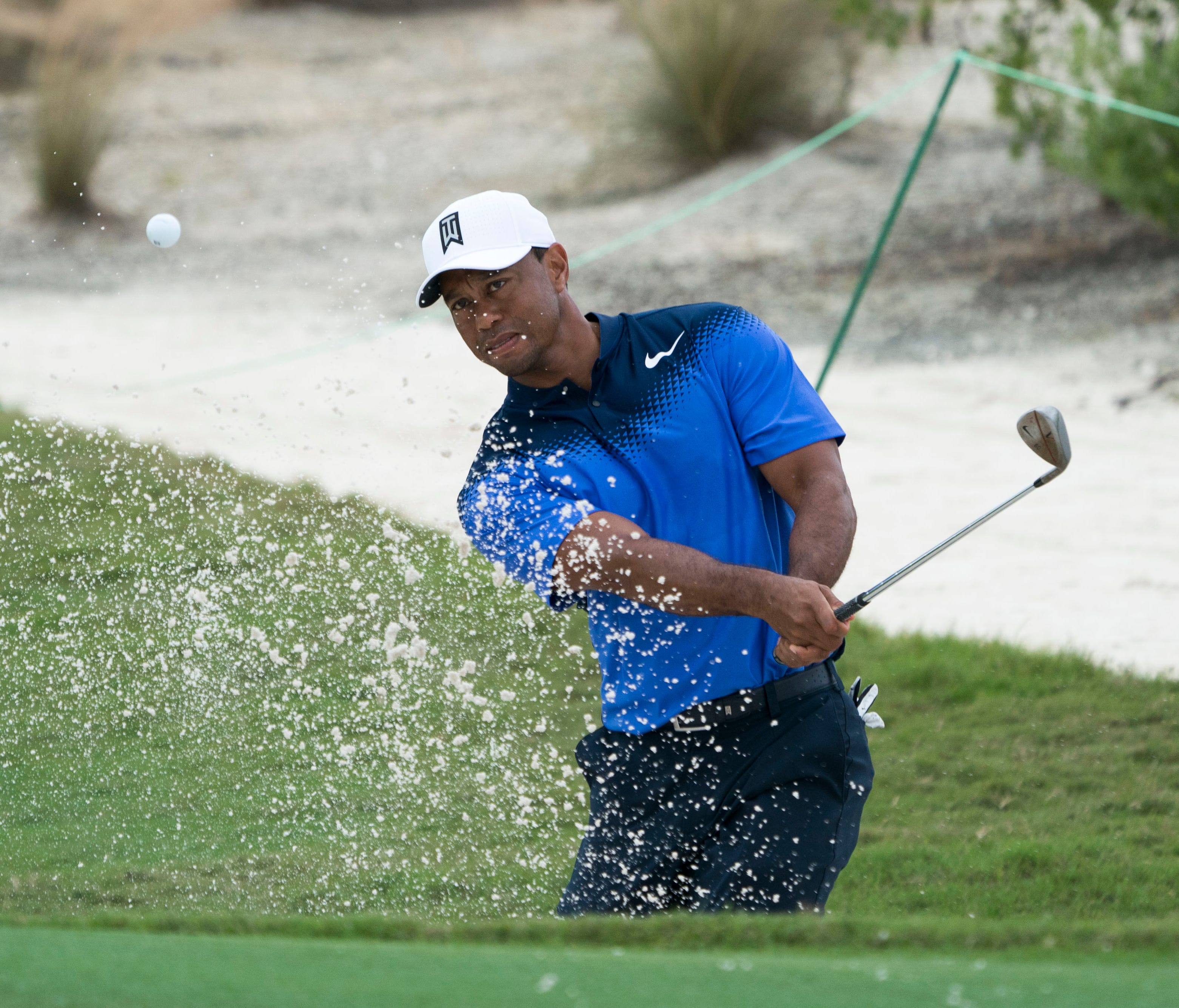 Tiger Woods hits out of a green side bunker on the ninth hole during a practice round in New Providence, Bahamas for the Hero World Challenge golf tournament at Albany.