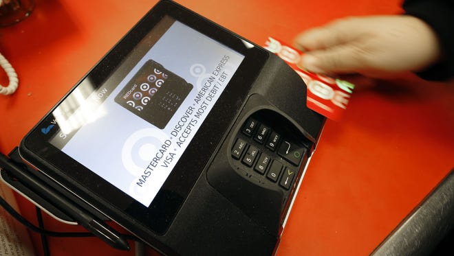 In this Friday, Nov. 28, 2014 file photo, a shopper pays for her purchases at a Target store in South Portland, Maine. Criminals stole personal information from tens of millions of Americans in data breaches in 2014. Of those affected, one in three became victims of identity theft, according to research firm Javelin.