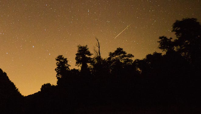 A Perseid meteor arcs over a line of trees in the Shenandoah National Park in the early morning hours of Thursday, Aug. 13, 2015.
