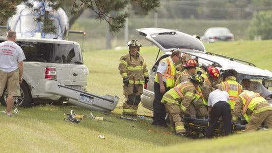 Firefighters, paramedics and University of Michigan Survival Flight personnel attend to a patient in one of two cars that were involved in a crash Tuesday afternoon on U.S. 23 south of Interstate 96 in Brighton Township. Four people were injured in the collision.