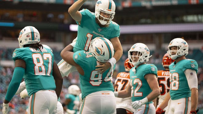 Dolphins quarterback Ryan Fitzpatrick (14) is lifted by defensive tackle Christian Wilkins after Wilkins scored his first NFL touchdown after catching a pass from Fitzpatrick.