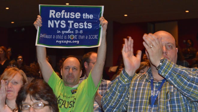 A parent holds up a sign urging others to opt out of New York's standardized tests for grades 3 to 8.