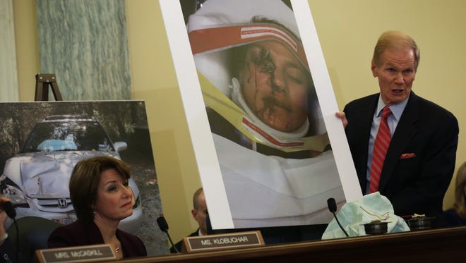 Sen. Bill Nelson, D-Fla., chairman of the Senate Commerce, Science and Transportation Committee, holds up a photo of Stephanie Erdman of Destin, Fla., showing her facial injury from the air bag explosion in her Honda.