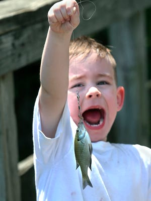 Rejoicing while holding the first fish he has ever caught.