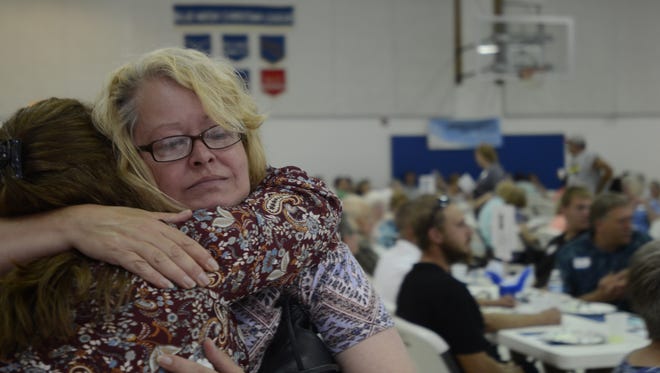 Elena Williams, left, a Trinity Lutheran School alumna and secretary for the church and formerly the school, embraces a tearful Bev Ostrander on Sunday, June 11, 2017, with the crowd of the day's potlock and farewell ceremony for the school behind them. Ostrander, who now lives in Cass City, said her son had attended Trinity through seventh grade.
