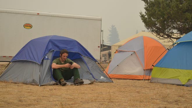Dan Hoffman, 23, of Missoula, checks his phone from his tent at the Rice Ridge Fire incident command post outside Seeley Lake. Excluding a three-day break, Hoffman has been on the Rice Ridge Fire for about 30 days.