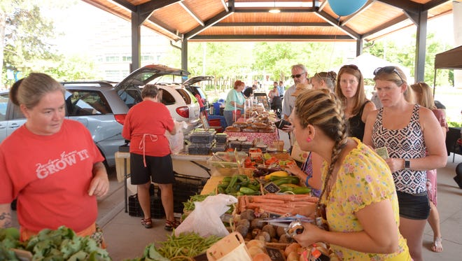 This 2018 photo shows customers purchasing Avalon Farms produce at the Battle Creek Farmer's Market at Festival Market Square.
