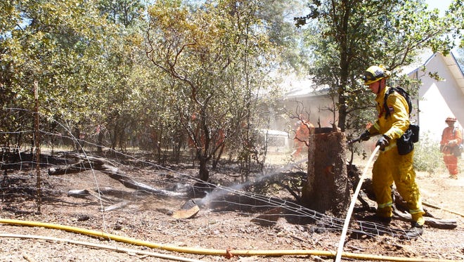 Firefighters clean up a vegetation fire in Bella Vista that burned near several homes.