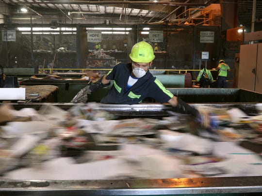 Employees pick contaminants off a conveyor belt in