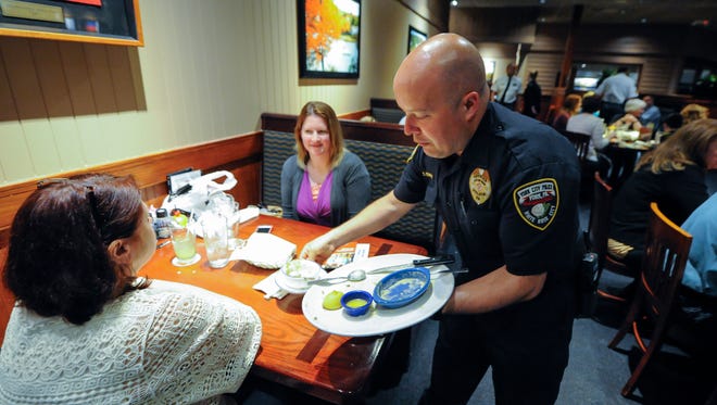 York City Police Officer Chris Perry clears a customer's table as local law enforcement take part in the 17th annual Cops and Lobsters fund raiser for York County Special Olympics at Red Lobster in Springettsbury Township, Thursday, April 20, 2016. John A. Pavoncello photo
