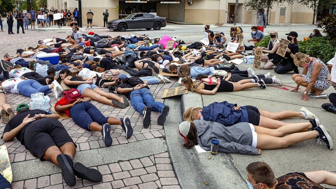 Young people lie in the street with their hands behind their backs at the intersection of N. Dixie Hwy. and Banyan Blvd. to protest George Floyd's death, June 5, 2020.