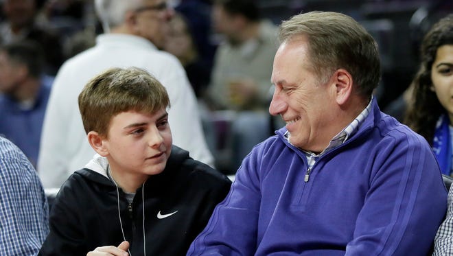 Michigan State basketball coach Tom Izzo, right, smiles at his son Steven while watching the Detroit Pistons play the Boston Celtics on April 8, 2015.