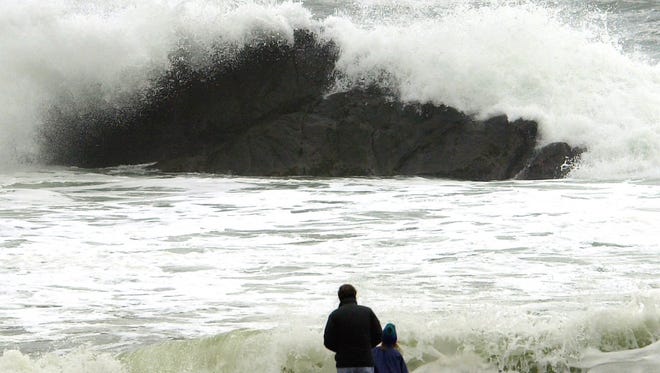 In this Nov. 28, 2001, file photo, people watch as storm-tossed waves crash over rocks near Depoe Bay, Ore.