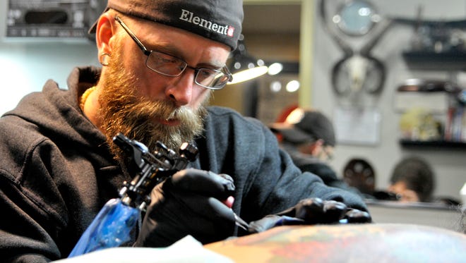 Trevor Muzik puts the finishing touches on a tattoo for Sauk Rapids client Beth Reimer.
