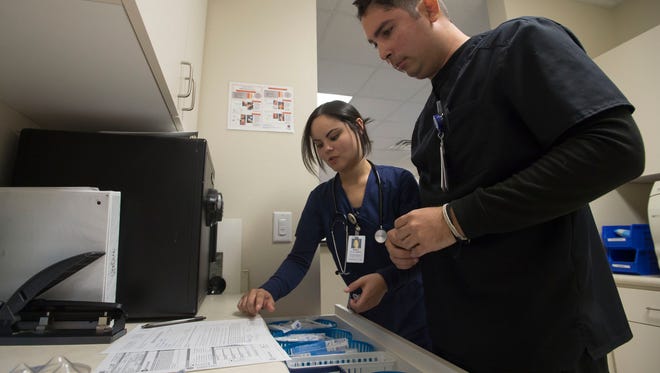 Medical scribe Ashley Delgado, left, and medical assistant Jose Caceres collect supplies and paperwork for administering flu vaccinations on Wednesday, March 14, 2018, at Miramont Family Medicine on West Drake Road in Fort Collins, Colo. 