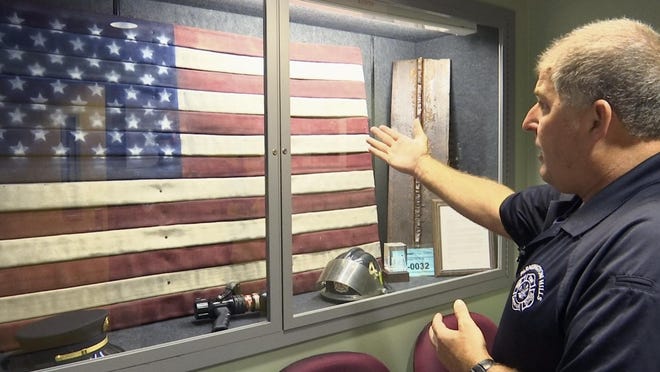 In this Aug. 22, 2016, image taken from video, EMS Coordinator Jim Etzin motions toward a glass case at the Farmington Hills Fire Department in Farmington Hills, Mich. The case contains items that commemorate the efforts of first responders during the Sept. 11, 2001, terror attacks. Etzin, then a Farmington Hills firefighter/paramedic, and eight other members of southeastern Michigan's firefighting community took part in a 755-mile walk from the Ambassador Bridge in Detroit to the Brooklyn Bridge a month after the attacks. (AP Photo/Mike Householder)