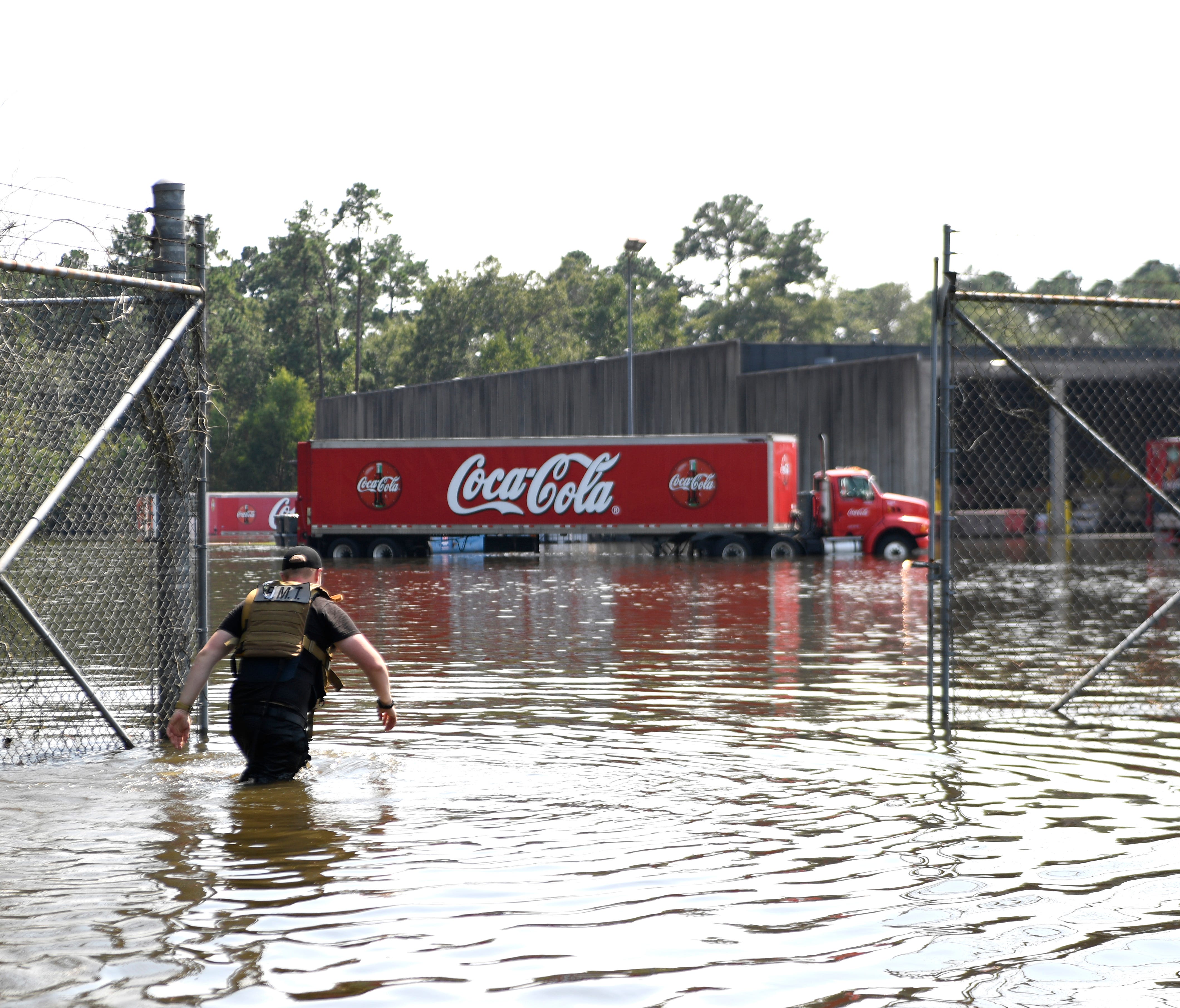 Sam Byers, an EMT from Arlington, Texas, wades past the gates of the Coca-Cola warehouse in Beaumont to get uncontaminated water on Sept. 2, 2017.