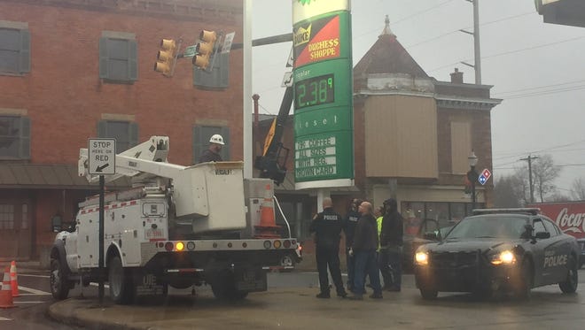 Police watch as utility workers support a traffic light post that was bent Friday in Shelby.