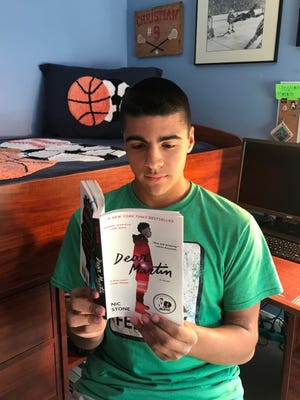 Amesbury High School sophomore Christian Mangini reads "Dear Martin," a book about a Black college student faced with racism and police abuse, as part of the school's Summer Reading Program.