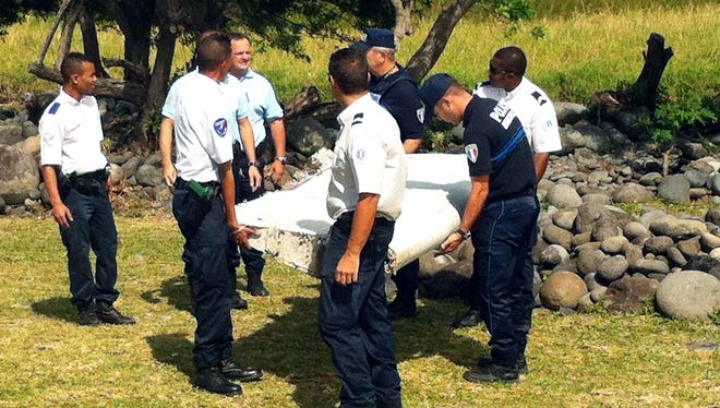 Police and gendarmes carry a piece of debris from an unidentified aircraft found in the coastal area of Saint-Andre de la Reunion, in the east of the French Indian Ocean island of La Reunion, on July 29, 2015.