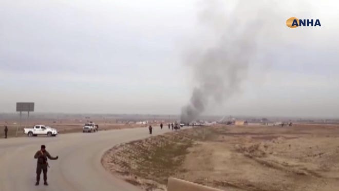 This frame grab from video provided by Hawar News, ANHA, the news agency for the semi-autonomous Kurdish areas in Syria, shows Kurdish fighters standing guard at the site of a suicide attack near the town of Shaddadeh, in Syria's northeastern province of Hassakeh, Syria, Jan. 21, 2019.