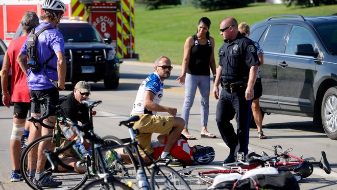 Interpreter, Robert Skarsbakk looks around while kneeling over Harald Vik, 71 after Vik and interpreter, Torben Loekaas were struck by a car while riding a tandem bicycle north on Marion Road near Madison Street Friday, Aug 22, 2014. Vik, a blind and deaf Norwegian was on a multi-day ride from Brookings to Lincoln, Neb.