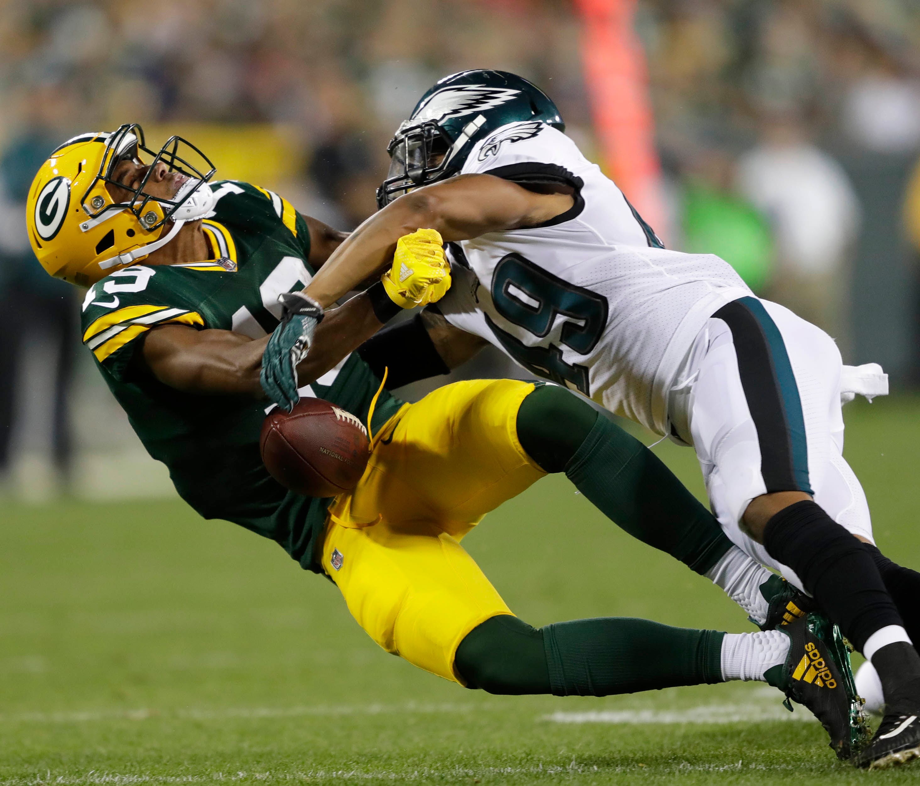 Green Bay Packers wide receiver Malachi Dupre (19) drops the ball as he is hit hard by Philadelphia Eagles defender Tre Sullivan in the second half in a preseason NFL game at Lambeau Field.